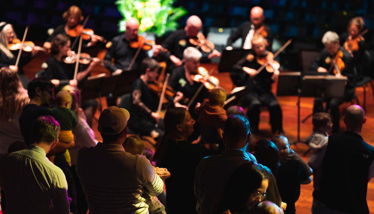 Barn og foreldre står og danser til orkestermusikk